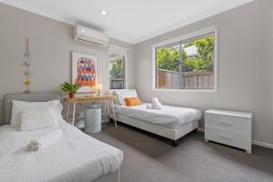 a bedroom with two beds and a table and window at Spacious 4-Bed House with Secure Parking in Brisbane