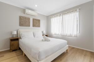 a white bedroom with a large bed and a window at Spacious 4-Bed House with Secure Parking in Brisbane