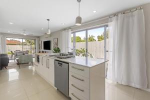 a kitchen with white cabinets and a large window at Spacious 4-Bed House with Secure Parking in Brisbane