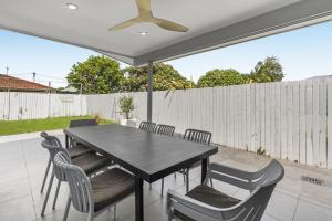 a dining table with chairs and a ceiling fan at Spacious 4-Bed House with Secure Parking in Brisbane +12 photos