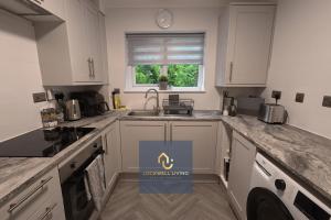 een keuken met witte kasten, een gootsteen en een raam bij Chalfont Haven 