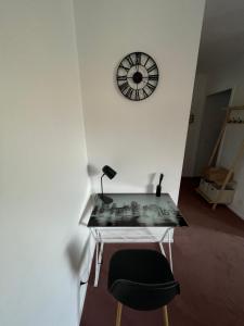 a desk with a chair and a clock on a wall at Appartement Saint Genis Pouilly Cern in Saint-Genis-Pouilly