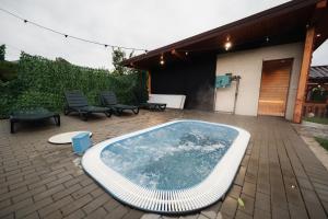 a swimming pool on a patio with chairs and a building at CABANA ZIMBRU in Băile Borşa