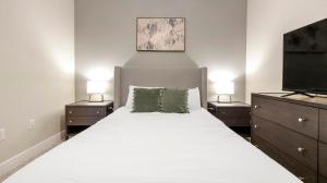 een slaapkamer met een wit bed en een flatscreen-tv bij Landing Modern 2BD Gym Pool in Kelim +125 foto's