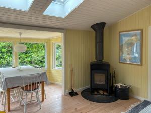 a dining room with a stove in a room with a table at Summerhouse Close To Nature And Beach in Rørvig