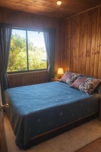 une chambre avec un grand lit avec une fenêtre dans l'établissement Cabañas los Jardines de Lican ray, à Licán Ray