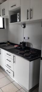a kitchen with white cabinets and a black counter top at Grace Villas 30 in East London +10 photos