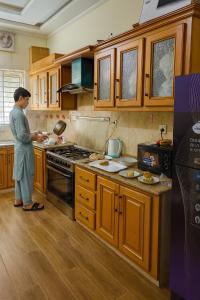 een vrouw die in een keuken staat en eten klaarmaakt bij The Canvas Stay in Islamabad