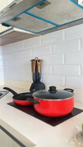 a red pan sitting on a kitchen counter with utensils at Modern Studio IT Park Fast Wi-Fi, Pool,Netflix in Sampong +2 photos
