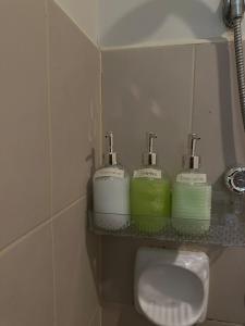a bathroom with three soap dispensers on a shelf above a sink at Modern Studio IT Park Fast Wi-Fi, Pool,Netflix in Sampong