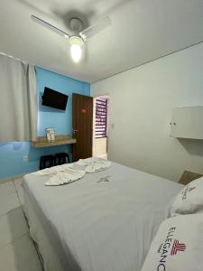 ein Schlafzimmer mit einem großen weißen Bett mit Deckenventilator in der Unterkunft Hotel Ellegance in Salvador