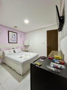 ein Schlafzimmer mit einem Bett und einem Schreibtisch mit einem Fernseher in der Unterkunft Hotel Ellegance in Salvador