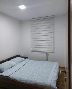 a bedroom with a bed and a window with a blind at Apartman Pale - Biljana in Pale