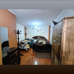 a bedroom with two beds and a wooden dresser at Hospedaje secretos in Huancayo