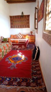 een kamer met een rood tapijt en kaarsen op de vloer bij La maison de palmeraie in Tamnougalt