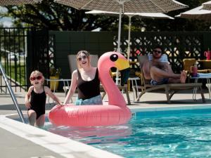Eine Frau und ein Kind befinden sich in einem Pool mit einem rosa Schwan. in der Unterkunft Colony House Motor Lodge in Roanoke