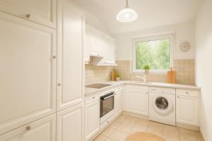 eine weiße Küche mit Waschmaschine und Fenster in der Unterkunft Ferienwohnung Meinerzhagen in Meinerzhagen + 9 Fotos