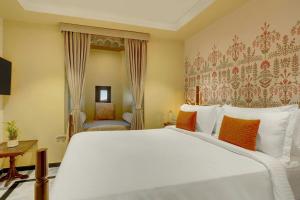 a bedroom with a large white bed with orange pillows at The Fern Bambora Fort Udaipur, Bambora, Series by Marriott in Udaipur