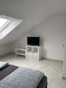 een witte kamer met een bed en een televisie bij Sunshine FeWo in Rust