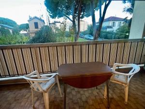 een houten tafel en 2 stoelen op een balkon bij Cosy studio plages Antibes in Antibes