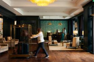 a woman walking through a room with a room with people at The Spectator Hotel in Charleston