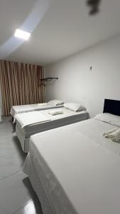 een rij van drie bedden in een kamer bij Pousada Flat Lourdes Residence in Angicos