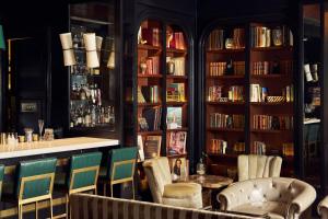 a library with chairs and a table and books at The Spectator Hotel in Charleston