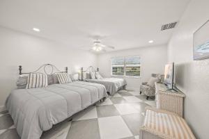 a bedroom with two beds and a couch and a chair at Jamaica Royale Beach Villa in Siesta Key