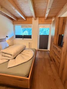 a bedroom with a bed and a tv and two windows at Haus Antonia in Kauns