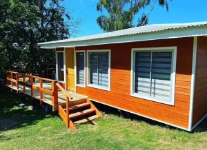 a small house with a large deck on the grass at Cabaña Lago Ranco in Ranco
