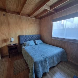una camera da letto con un letto con un piumone blu e una finestra di Los Gladiolos a Melipeuco