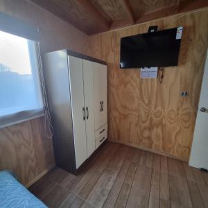 una camera da letto con frigorifero e TV a parete di Los Gladiolos a Melipeuco