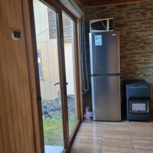 una cucina con frigorifero in acciaio inossidabile e porta scorrevole in vetro di Los Gladiolos a Melipeuco