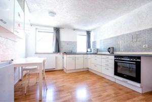 een keuken met witte kasten en een tafel en een tafel en een fornuis bij Nest-Unterkunft in Bad Überkingen