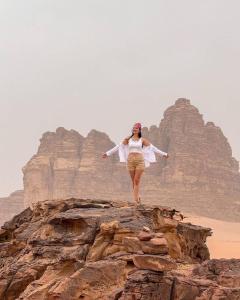 Una donna in piedi su una roccia nel deserto di Princess luxury camp a Wadi Rum