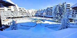 a courtyard covered in snow in front of buildings at Konaci Prime Center in Kopaonik