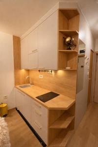 a kitchen with white cabinets and a wooden counter top at Konaci Prime Center in Kopaonik +4 photos