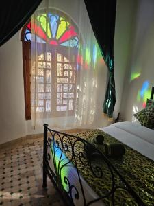 a bedroom with a bed with a stained glass window at Chambres Émeraude et Rubis - Riad Lotus Bleu in Fès