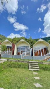 a house with two large windows on a grass field at Diiza Glamping Tawangmangu Private Pool No BBQ in Tawangmangu
