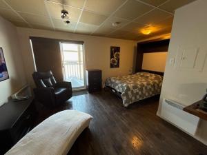 a bedroom with a bed and a chair in it at Studio #1 avec balcon tout inclus in Baie-Comeau