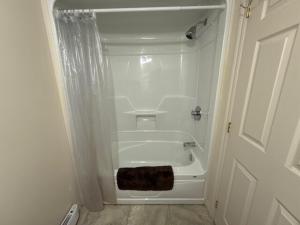 a bathroom with a bath tub with a towel next to a door at Studio #1 avec balcon tout inclus in Baie-Comeau