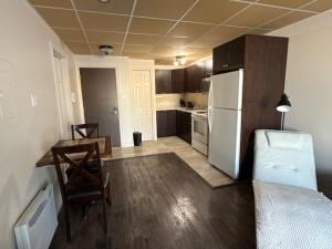 a kitchen with a table and a white refrigerator at Studio #1 avec balcon tout inclus in Baie-Comeau