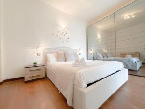 a white bedroom with a large white bed and a mirror at Elegante appartamento - Aeroporto - Porto - WiFi - Casa Gelsomino in Genoa