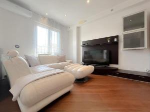 a living room with a white couch and a television at Elegante appartamento - Aeroporto - Porto - WiFi - Casa Gelsomino in Genoa