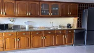 a kitchen with wooden cabinets and a stainless steel refrigerator at Apartamento - The Light House in Peniche