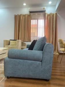 ein Wohnzimmer mit einem blauen Sofa vor einem Fenster in der Unterkunft Maculusso City Stay in Luanda