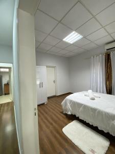 Schlafzimmer mit einem weißen Bett und Holzböden in der Unterkunft Maculusso City Stay in Luanda + 9 Fotos