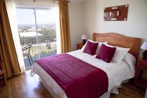 una camera da letto con un letto grande e una grande finestra di Hotel y Cabañas Portal del Inca a Caldera