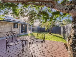 zwei Stühle und ein Tisch auf einem Holzdeck in der Unterkunft Ultimate Beachside Haven in Cabarita - Pet Friendly in Cabarita Beach