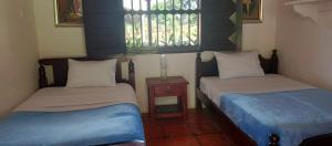 een kamer met 2 bedden, een tafel en ramen bij Finca Hotel El Juncal in Venecia